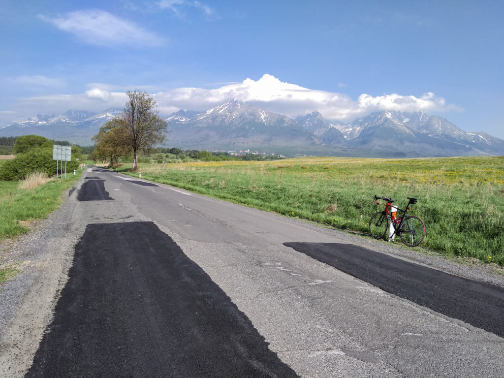 Szeroga droga asfaltowa o złej nawierzchni, w tle Tatry